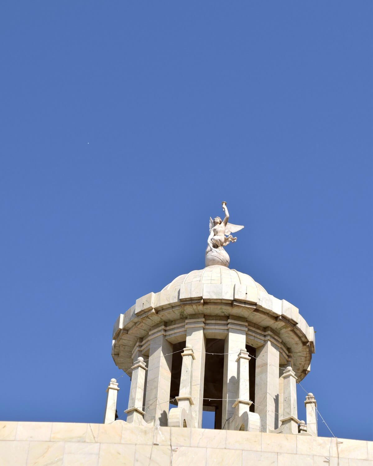 The dome of Malhara House crowned by a winged statue against blue sky